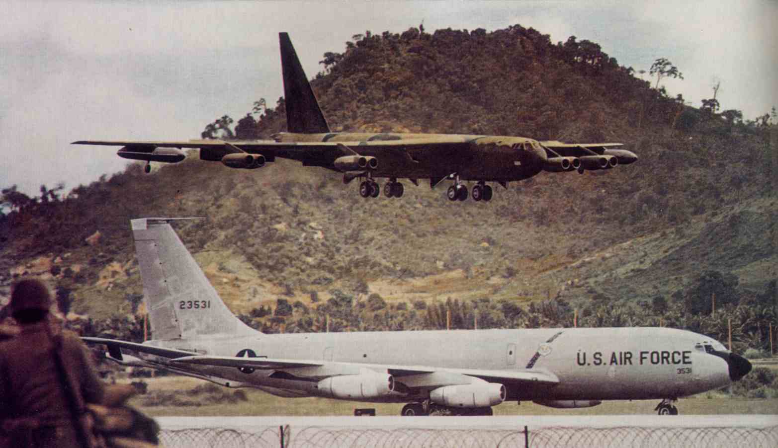 Thai Marine Guard watches B-52 land as KC-135 taxis for takeoff with Buddha Mountain in background.